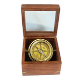 A brass gimbal compass with a wooden box, showing the compass needle and intricate brass work.